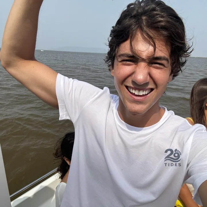 A grinning boat selfie on open water, wearing the 29 Tides shirt.