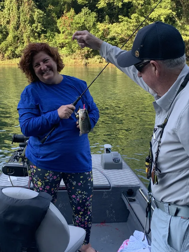 An angler grins with a trout on her line while the guide reaches for it.