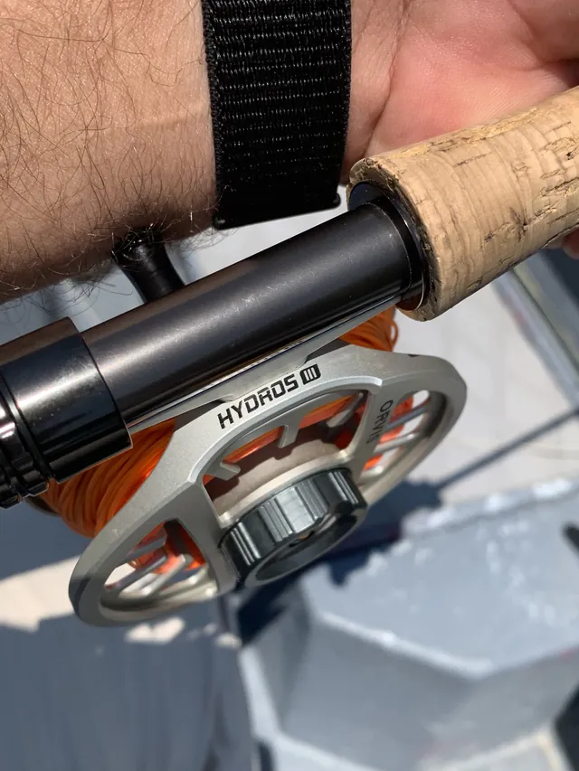 A fly reel and cork grip held over the boat, orange line on the spool.